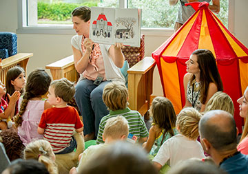 Photo of a women reading a book to children. Links to Closely Held Business Stock